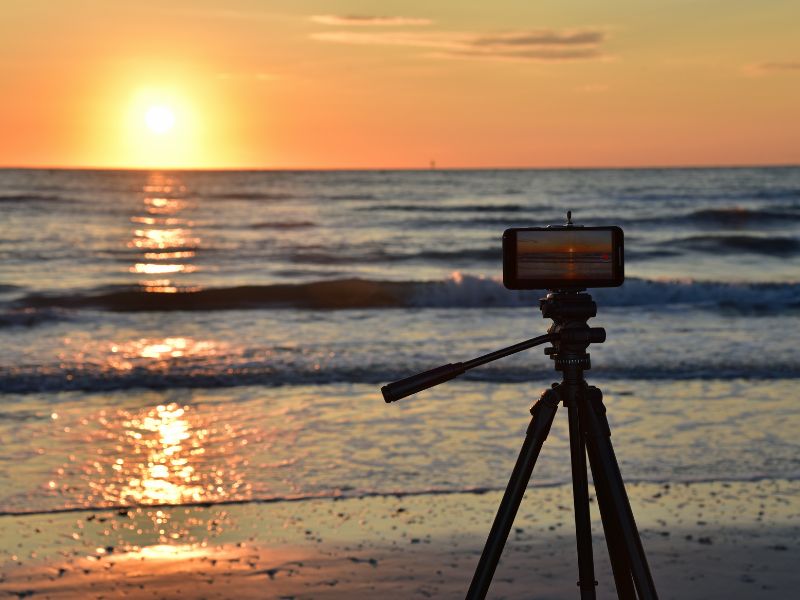 Camera tripod photgraphing sunset over ocean